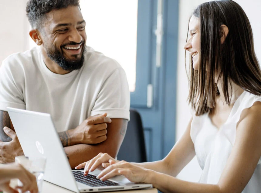 Bild von zwei jungen Erwachsenen, die lachend am Laptop arbeiten